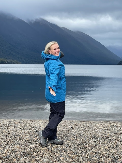 Georgie Discover Yourself In Adventure hiking on the pebbled shore of a lake