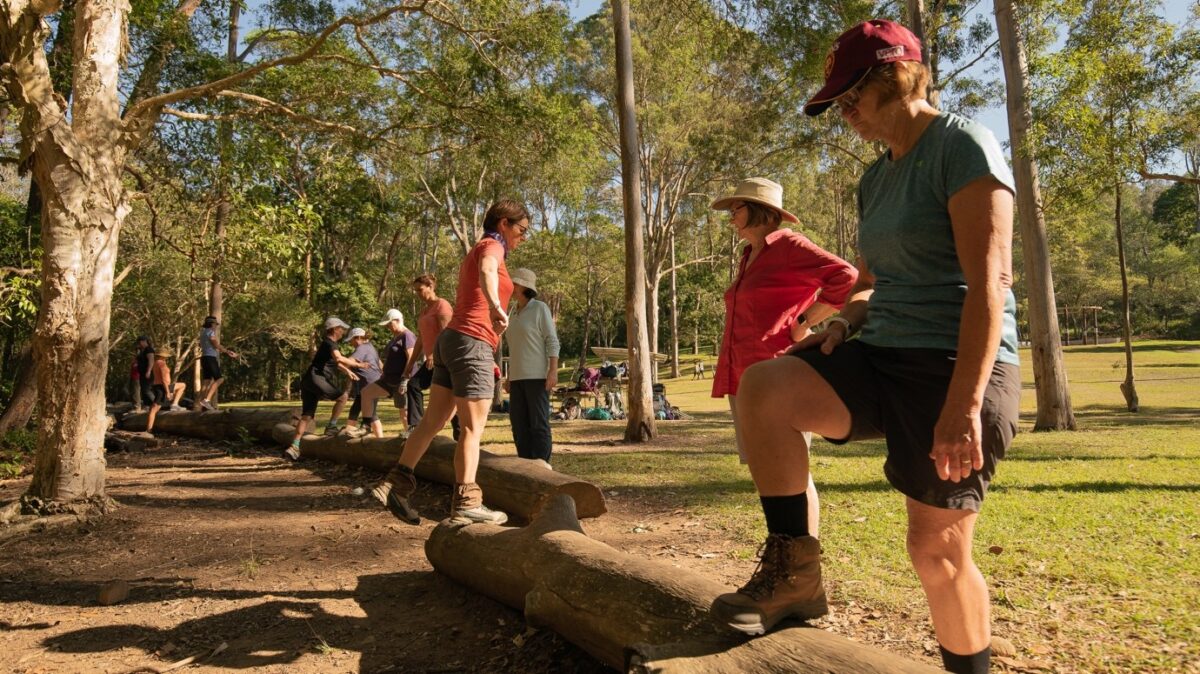Women hikers balancing on fallen logs during an outdoor fitness session in the forest
