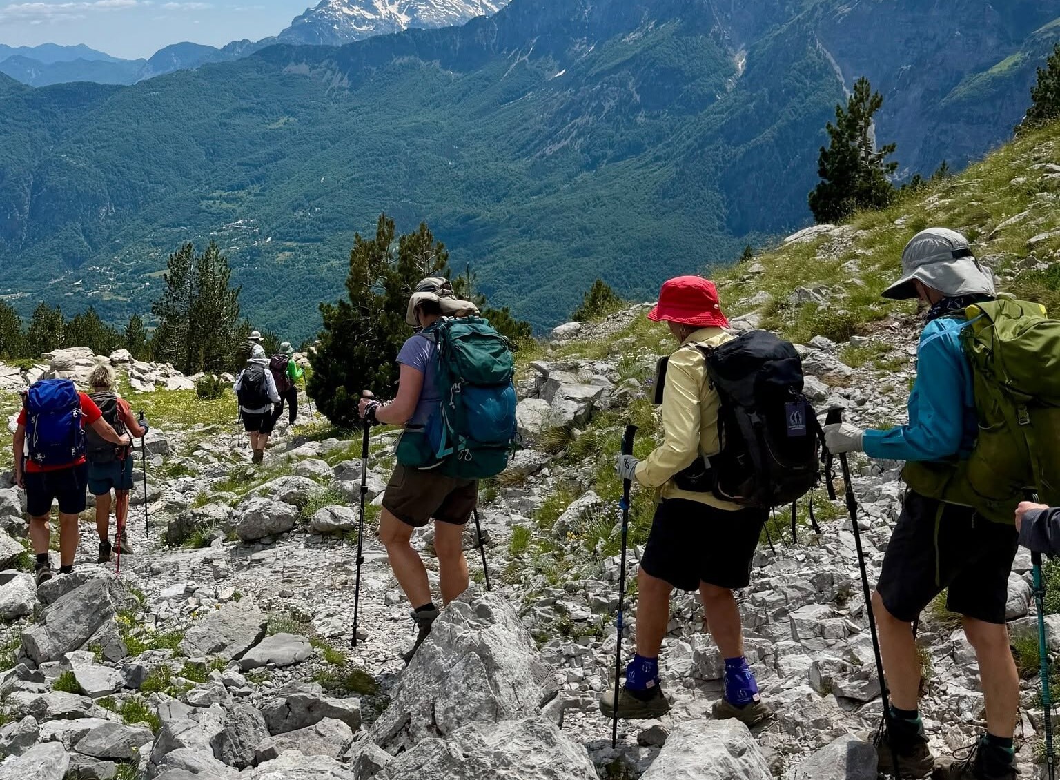 Women hikers trekking rocky mountain trail with gear